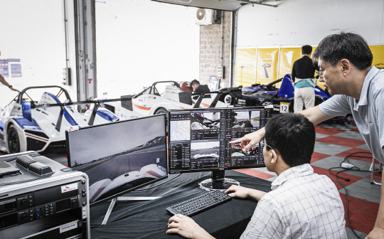 SK텔레콤과 삼성전자가 영암 국제자동차경주장에서 시속 210km로 달리는 차량으로 '28GHz 초고주파'를 활용한 데이터 전송과 생중계에 성공했다. SK텔레콤 연구원들이 차고지에서 5G 생중계로 운전 상황을 지켜보고 있다.    SK텔레콤 제공